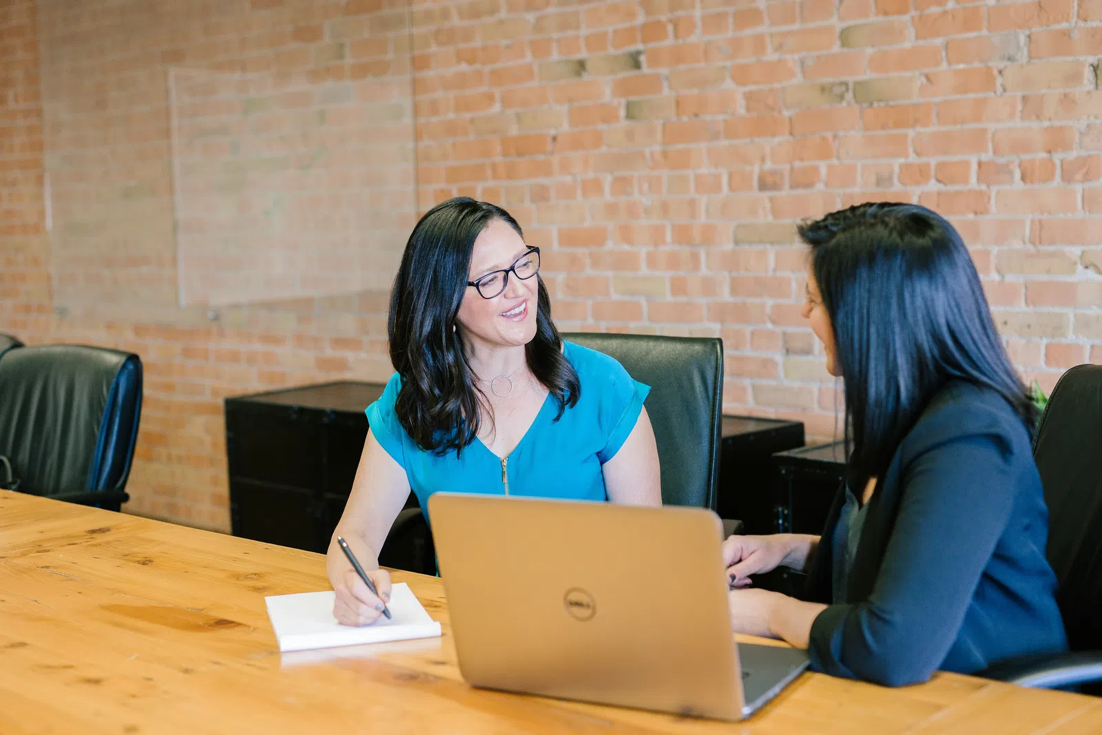 a couple of women sitting at a table looking at a laptop