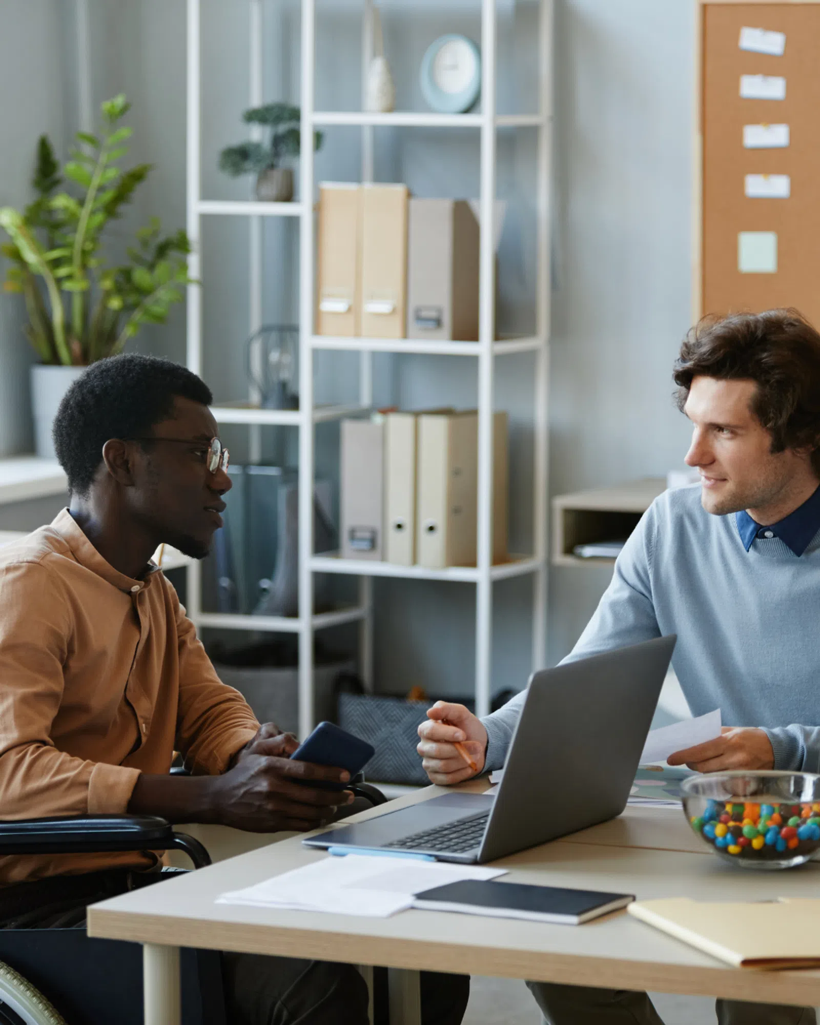 men sitting at a table looking at a laptop