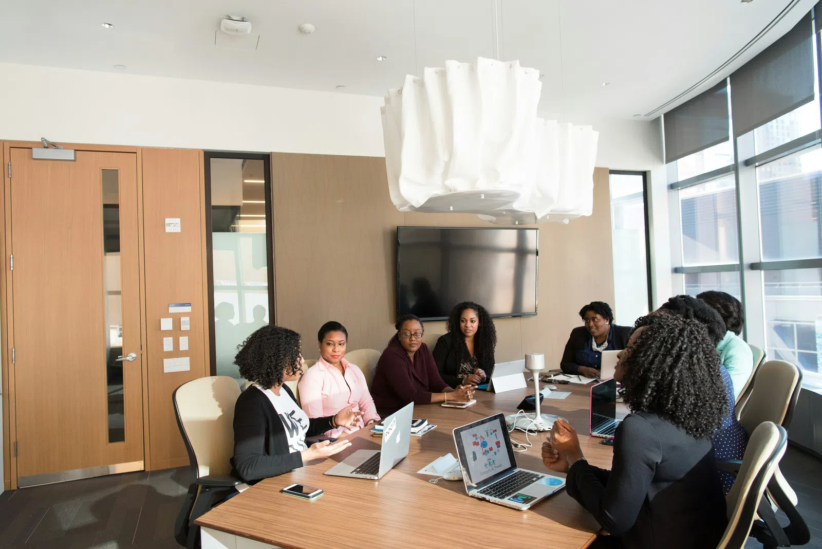 a group of people sitting around a table with laptops