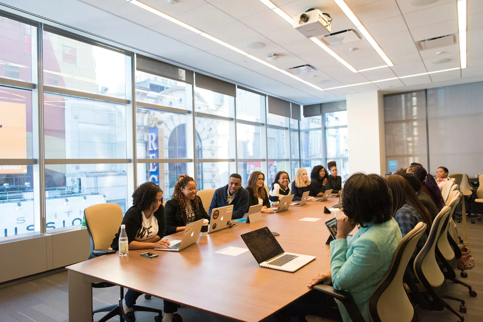 a group of people sitting around a table with laptops