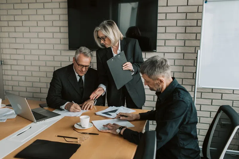 Three business professionals collaborating over documents in a modern office meeting room
